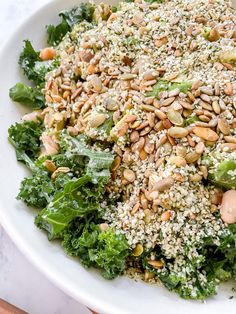 a white bowl filled with greens and nuts