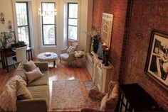 a living room filled with furniture and lots of windows next to a fire place in a brick wall