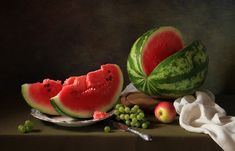 watermelon slices, grapes and apples on a plate with a cloth next to them