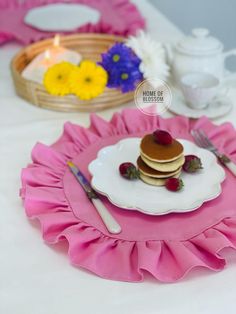 a plate with some pancakes on it next to a basket full of flowers and tea