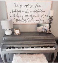 a piano sitting next to a lamp on top of a wooden table with a sign above it