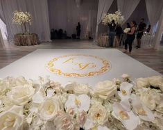 white flowers are arranged on the floor in front of a monogrammed wedding sign