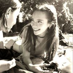 two young women sitting on the ground looking at their cell phones