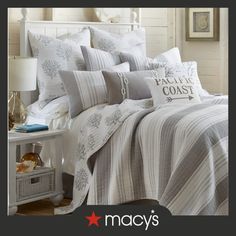 a bed covered in white and grey comforter next to a night stand