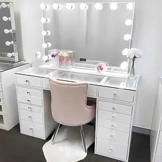 a white vanity with lights on it and a pink chair in front of the mirror