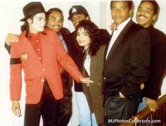 a group of people standing next to each other in front of a white wall wearing suits and hats