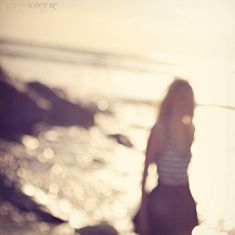 a woman standing on the beach in front of the ocean with her back to the camera