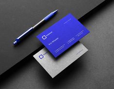 a blue business card sitting on top of a desk next to a pen