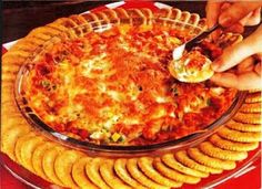 a person scooping food out of a casserole dish with crackers on the side