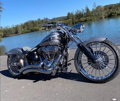 a black motorcycle parked on the side of a road next to a body of water