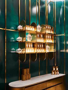 shelves with candles and teapots on them against a green wall