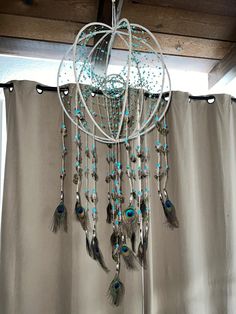 a chandelier with feathers hanging from it's sides and beads on the bottom