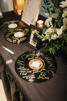 a table topped with two black records covered in autographs and flowers next to candles