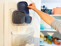 a man is holding two plastic containers in front of the refrigerator door and reaching for it