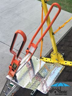 an orange and yellow scissor attached to the side of a metal object on a sidewalk