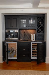 a kitchen with black cabinets and an open wine cooler in the center, along with wood flooring