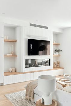 a living room with white walls and wooden shelves on either side of the wall is a flat screen tv