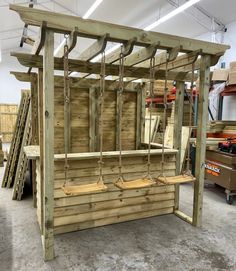 a wooden swing set in the middle of a workshop