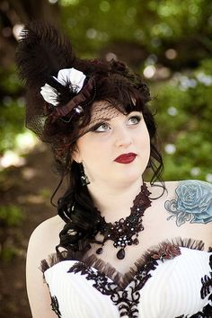 a woman wearing a black and white dress with feathers on her head