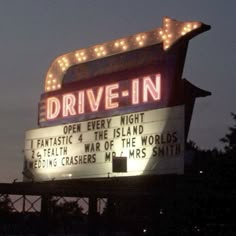 the drive - in sign is lit up at night with lights on it's sides