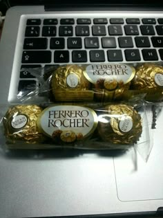 three chocolates wrapped in cellophane are sitting on top of a laptop keyboard