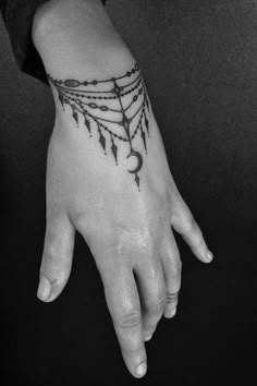 a person's hand with a black and white tattoo design on the left wrist