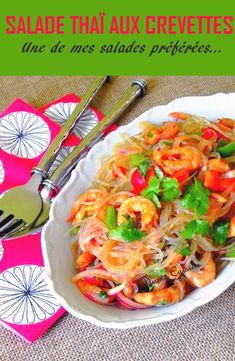 a bowl filled with noodles and shrimp on top of a table next to utensils