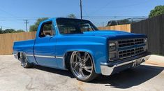 a blue truck parked in a driveway next to a fence