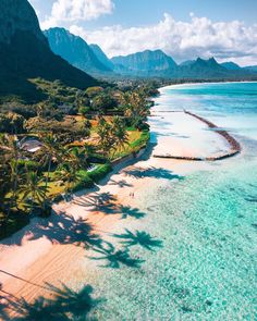 an aerial view of a tropical beach with palm trees and mountains in the back ground