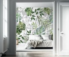 an open door leading to a white bedroom with green leaves on the wall