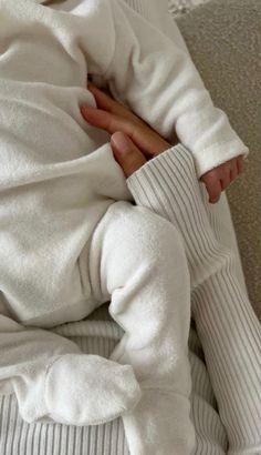 a baby wrapped in a white sweater and striped pants