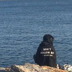 a man sitting on top of a rock next to the ocean