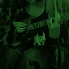 a woman playing guitar with a cat sitting on her lap