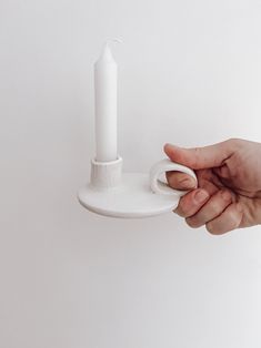 a hand holding a white candle holder on a wall