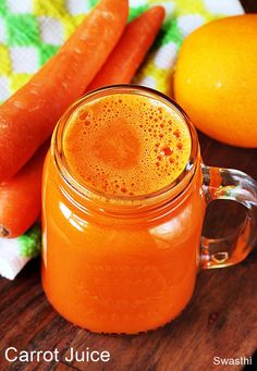 carrot juice in a mason jar next to oranges