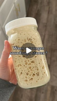 a person holding a glass jar filled with liquid and text that reads, want a younger sourdoun in starter?