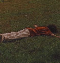 a person laying in the grass with a frisbee near by on their back