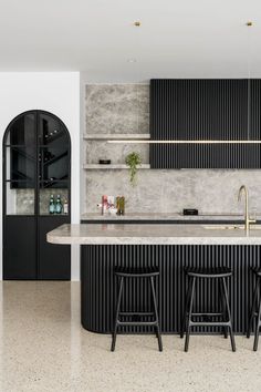 a kitchen with black cabinets and marble counter tops