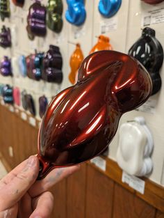 a person holding up a shiny object in front of a wall with many different colors