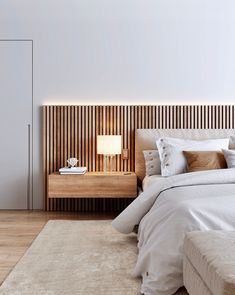 a bed with white sheets and pillows in a bedroom next to a wooden headboard