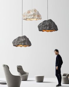 a man is standing in front of some chairs and hanging lights that look like rocks