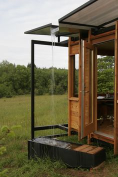 an outhouse in the middle of a field with grass and trees around it,