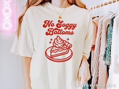 Show off your baking prowess with our "No Soggy Bottoms" shirt, featuring a fun retro font and a slice of pie illustration 🥧! Perfect for bakers who know the importance of a perfectly baked crust, this shirt adds a playful touch to your kitchen attire. Soft and comfy, it's great for both baking sessions and casual outings. Whether you're whipping up a pie or just love a good baking pun, this shirt is a delicious addition to your wardrobe! 🌸 PRODUCT INFO  ✿ Super soft Comfort Colors® 1717 Unise Baker Shirts, Retro Font, Favorite Shirts, Comfort Colors, Pie, Tops & Tees, Adult Outfits, Unique Items Products, Wardrobe