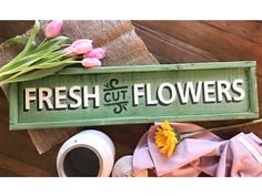 a sign that says fresh cut flowers next to a cup of coffee and some flowers