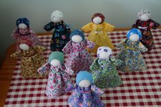 a group of cloth dolls sitting on top of a checkered tablecloth covered table