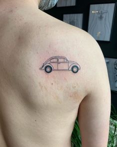 a small car tattoo on the back of a man's left shoulder and chest