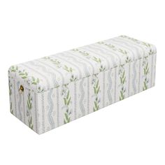 an upholstered storage box with green and white designs on the lid, in front of a white background