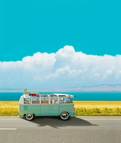 an old vw bus with surfboards on top driving down the road by the ocean