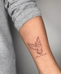 a small owl tattoo on the arm