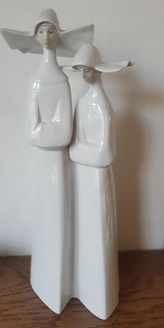 two white ceramic figurines standing next to each other